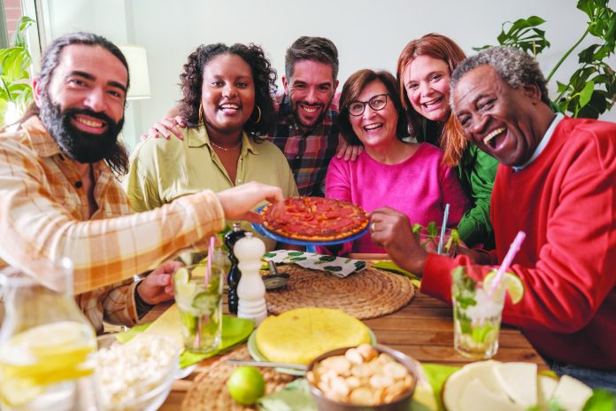 Group of friends gathered eating together and celebrating their