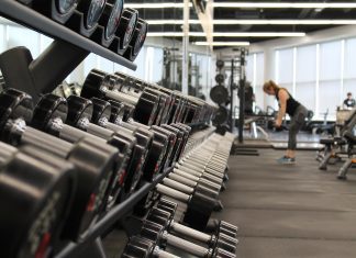 Racks of weights in a gym with people in the background