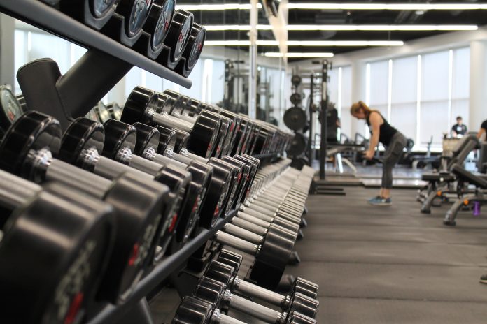 Racks of weights in a gym with people in the background