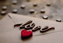 Love on a Shoestring Envelope with a wooden cutout of the word love on top of it