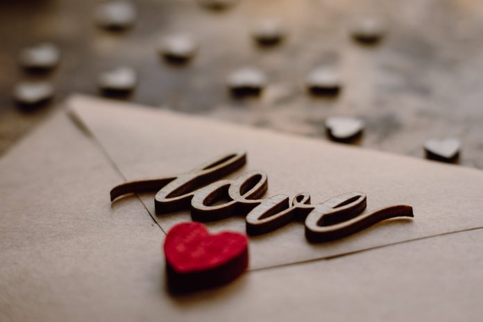 Envelope with a wooden cutout of the word love on top of it