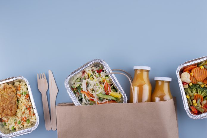 To go containers of salads, rice, and juice on light blue background